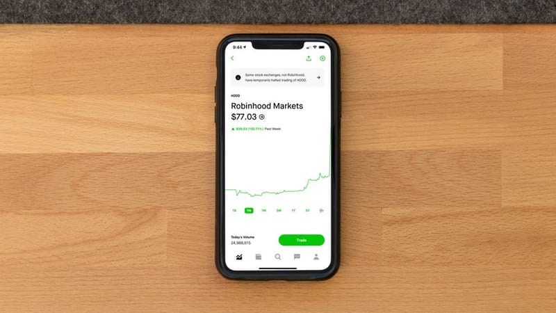 Investing app showing portfolio charts on a smartphone beside a laptop